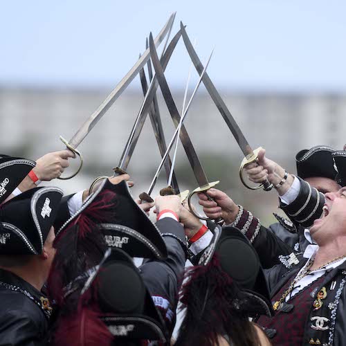People dressed as pirates holding swords together in the air